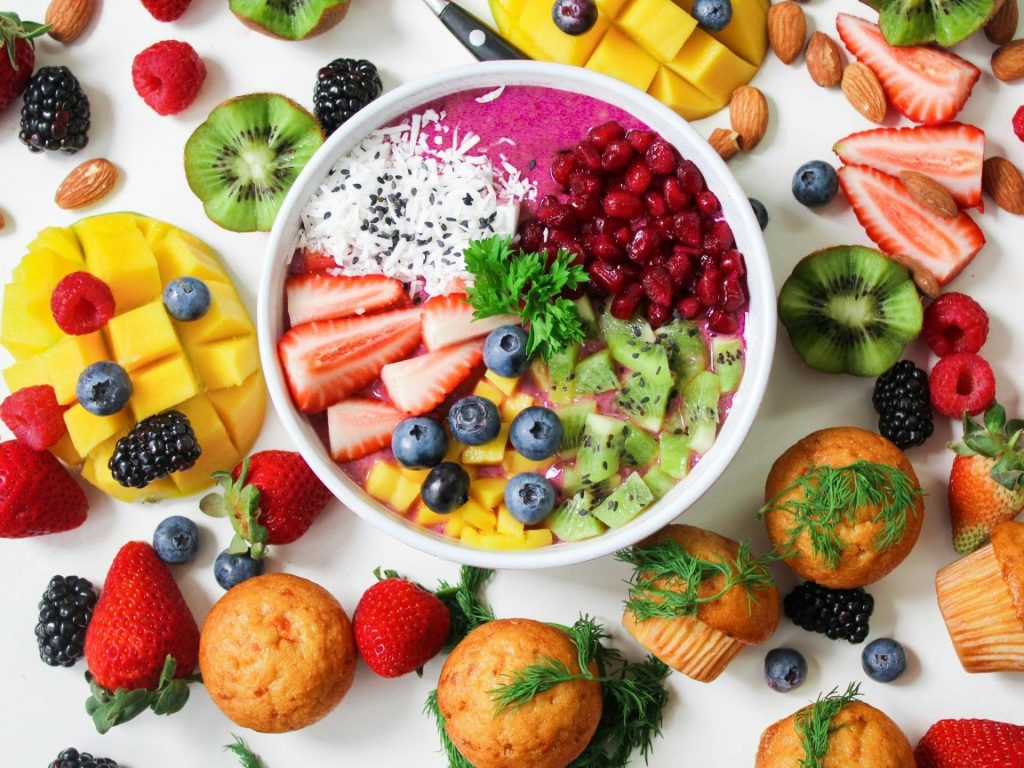 Bunte Smoothie-Bowl mit verschiedenen frischen Früchten und Muffins, perfekt für einen gesunden Snack.